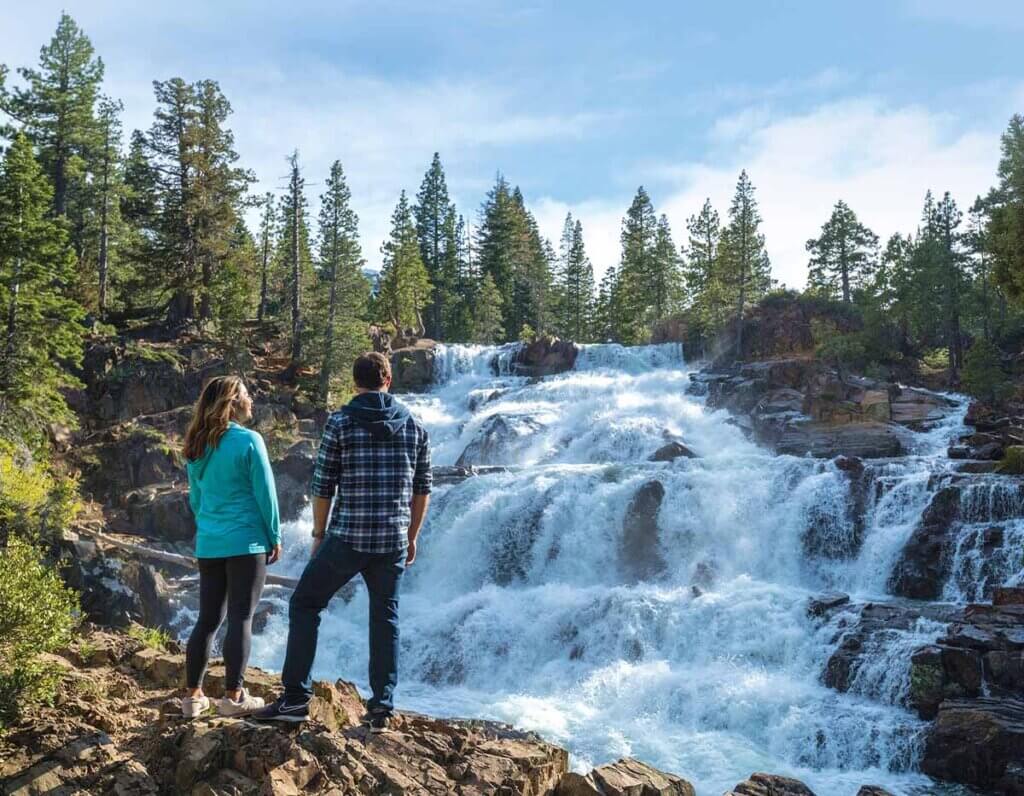 couple standing by lake tahoe waterfall