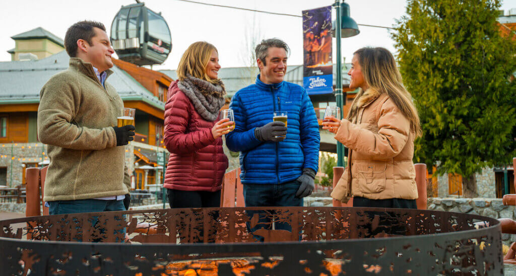 Friends enjoying apres drink by a fire pit at Heavenly Village
